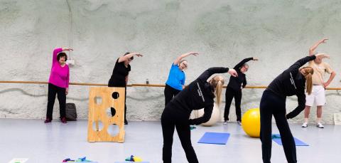 An exercise group stretching under the guidance of their instructors.