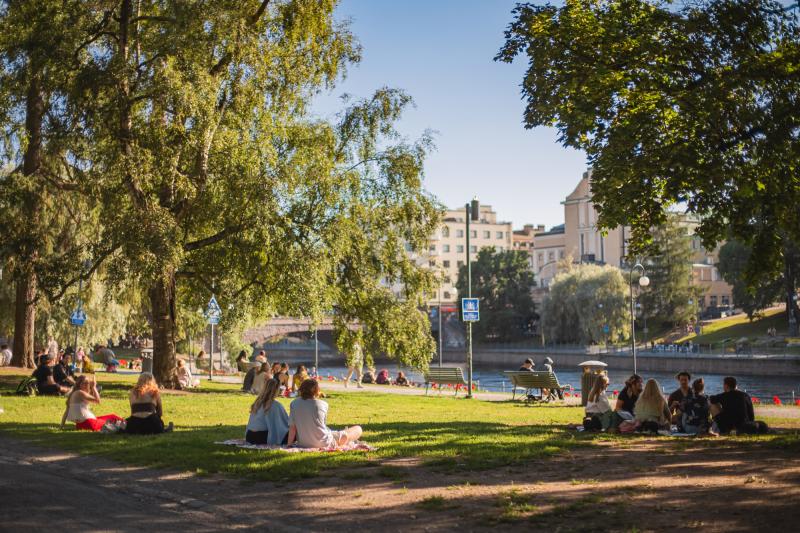People sitting on blankets in Koskipuisto Park on a summer day.