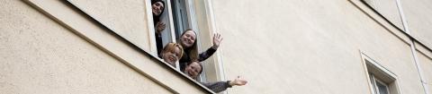 Tampereen lyseon lukion opiskelijoita heiluttaa koulun ikkunasta.