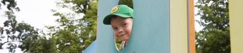 Lapsi kurkistaa leikkitelineen pyöreästä aukosta Pikku Kakkosen puistossa.