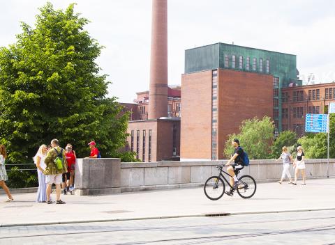 Pedestrians and a bicyclist on Hämeenkatu street on Hämeensilta bridge.