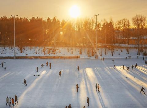 Ice skaters on the Sorsapuisto artificial ice rink, the sun shining low.