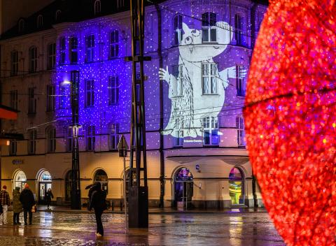 Muumiaiheinen valaistus rakennuksen seinällä Keskustorilla, etualalla punainen koristevalopallo.