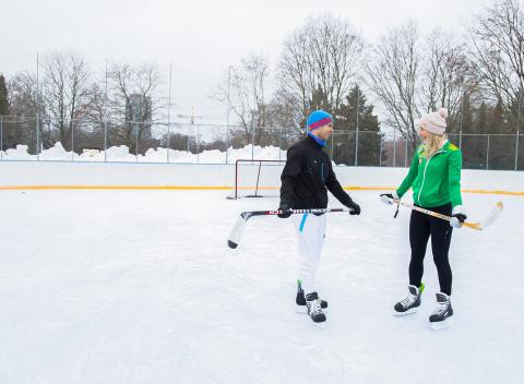 Two people wearing skates and holding sticks on the artificial ice rink in Sorsapuisto Park.