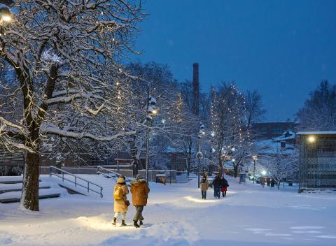 People walking in the snowy, twilight landscape of Koskipuisto Park.