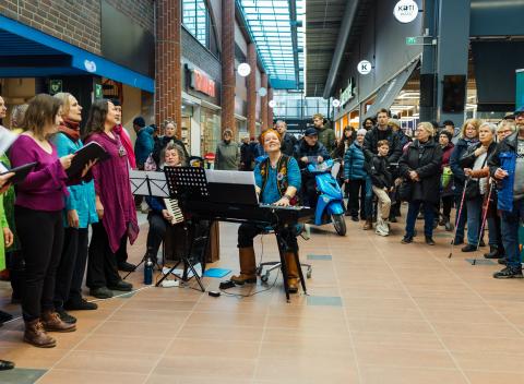 The choir performs in the lobby of the shopping center.