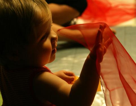 Vauva heiluttaa punaista sirkushuivia.