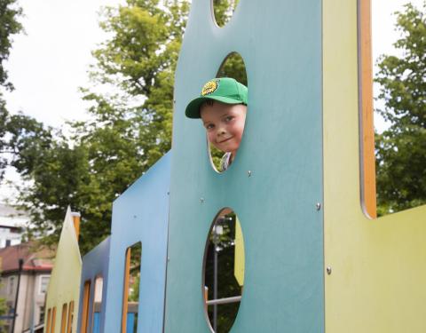 Lapsi kurkistaa leikkitelineen pyöreästä aukosta Pikku Kakkosen puistossa.