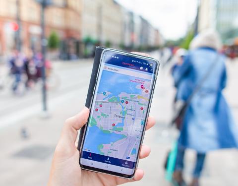 Kädessä älypuhelin, jonka näytöllä auki kartta Tampere.Finland mobiilisovelluksessa.