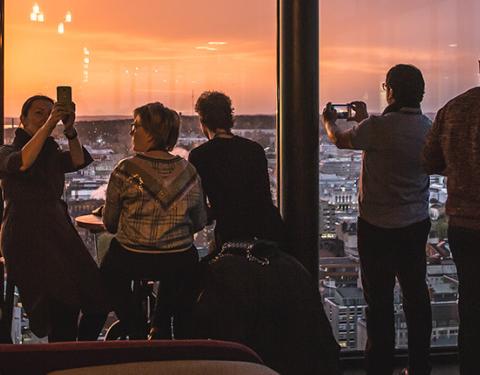 Ihmiset katsovat auringonlaskua Torni-hotellin ylimmästä kerroksesta