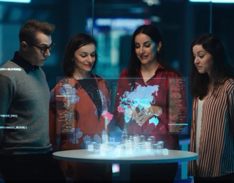 A group of persons standing around of a city hologram. 