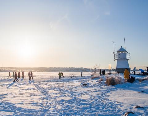 Ihmisiä aurinkoisessa talvimaisemassa Näsijärven jäällä Siilinkarin majakan lähellä.