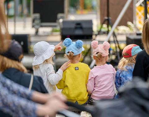 Children in their colourful clothes looking at a stage.