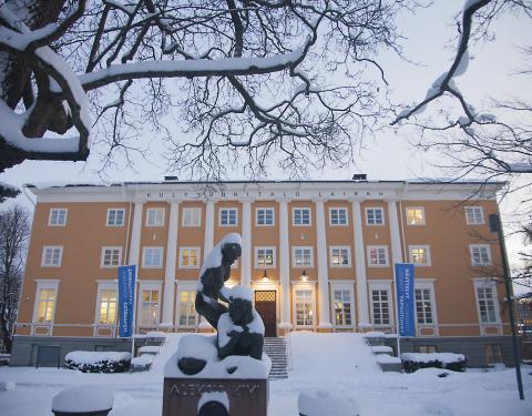 Iso keltainen vanha rakennus lumisessa maisemassa. 