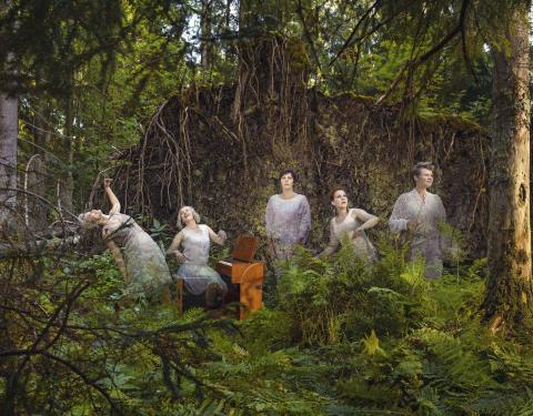 Ihmisiä soittimineen metsässä.