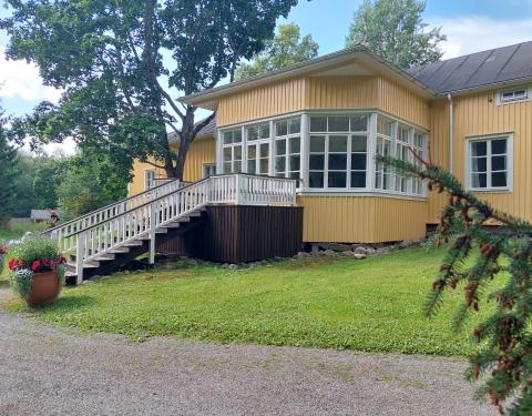 Keltainen kartanorakennus, jonka takana lasierkkeri.