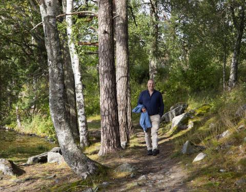 Henkilö kävelee puiden reunustamaa metsäpolkua pitkin.