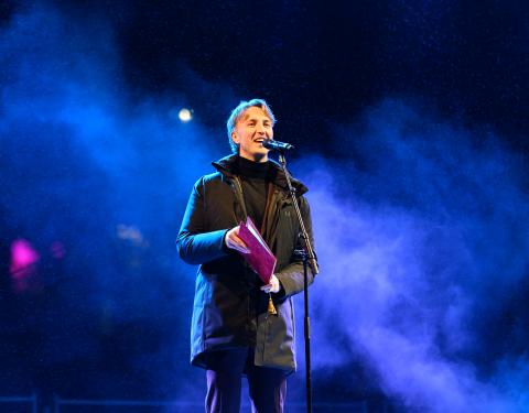 Pormestari Ilmari Nurminen puhuu ulkona mikrofoniin. On talvi-ilta ja pormestarin takana näkyy sinistä höyryä.