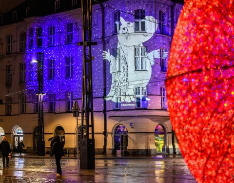 Moomin-themed lighting on the wall of a building in Keskustori Central Square, with a red decorative light globe in the foreground.