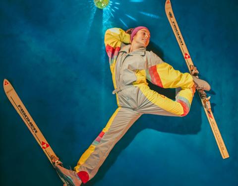 Hiihtoasuinen sirkusesiintyjä sinisellä taustalla