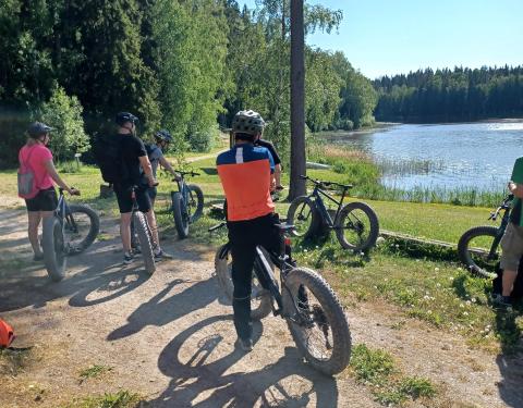 Pyöräilijöitä katselemassa järven rannalla.