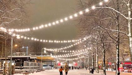 Aikuinen ja lapsi kävelevät talvisessa Hämeenpuistossa jouluvalojen alla