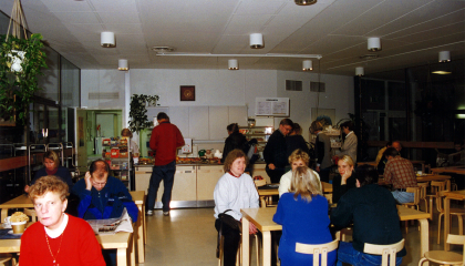 Henkilöitä kahvilassa. Taustalla on kahvilan tiski.