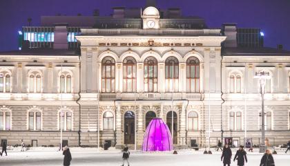 Keskustorin suihkulähteen suojakupu pinkissä valaistuksessa.