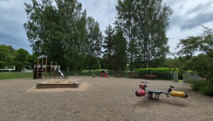 Isolammin leikkipaikan välineitä ja hiekkalaatikko. 