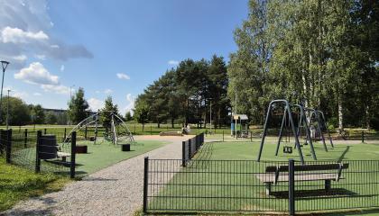 Jukolanpuiston leikkipaikka kuvattuna kauempaa aurinkoisena kesäpäivänä.