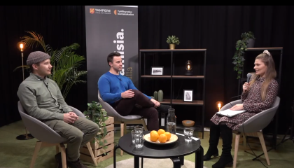 Kaksi miestä ja nainen juttelevat studiossa