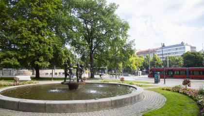 Suihkulähde Pyynikin kirkkopuistossa, taustalla ratikka.