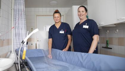 Koukkuniemen lähihoitajat suihkutuspisteessä. Kuvassa myös apukädeksi kutsuttu laite.