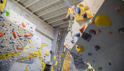 Henkilö kiipeilee boulder-seinällä.