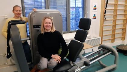 Kaksi hymyilevää fysioterapeuttia on kuntosalilla.
