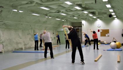 Seniorit tekevät tasapainoharjoituksia liikuntasalissa.