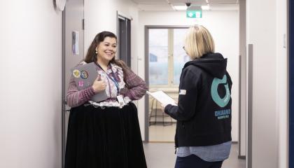 Kaksi henkilöä juttelee käytävällä. Toinen on romaniasussa ja toinen on pukeutunut Ohjaamon huppariin.