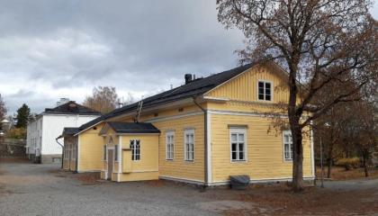 Harjun koulun keltainen koulurakennus etualalla, taustalla valkoinen koulurakennus ja pihapiiriä.