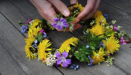 Luonnonkukista tehty kukkaseppele lankkulattialla.