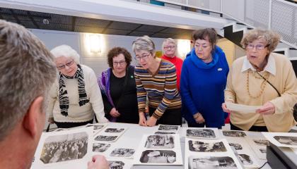 Seniorit katselevat pöydälle aseteltuja mustavalkoisia valokuvia.