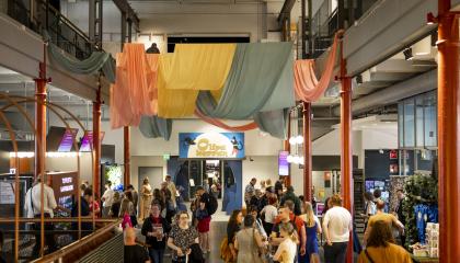 Vapriikin aulassa paljon ihmisiä, taustalla Olipa kerran -näyttelyn sisääntulo. Katossa kangaskoristeita roikkumassa.