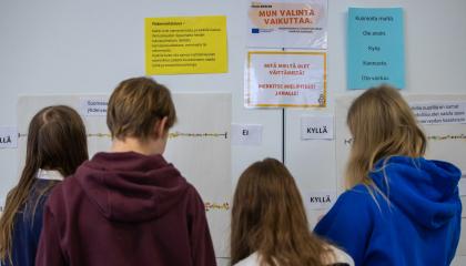 neljä nuorta seisoo seinän edessä, jossa lukee erilaisia vaikuttamiseen liittyviä lauseita