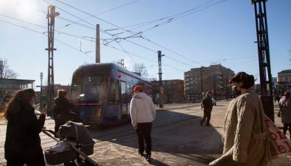 Hiekoitussepeliä Keskustorilla keväällä, kadulla kävelijöitä ja ratikka.
