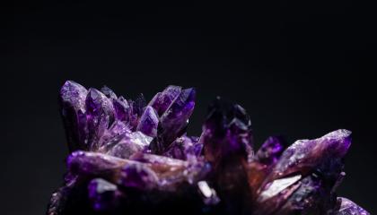 Violetti kivi, jossa useita isoja kiteitä mustalla taustalla. 