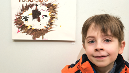 Lapsi ja hänen vasemmalla puolella seinässä kiinni oleva taideteos.