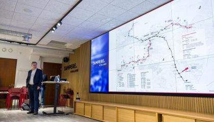 Henkilö kuvan vasemmassa laidassa esittelee raitiotien suunnitelmia isolta näytöltä.
