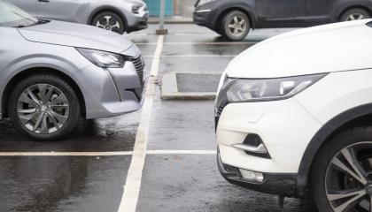 Henkilöautoja parkkiruuduissaan parkkipaikalla, autoista näkyy vain etuosat.