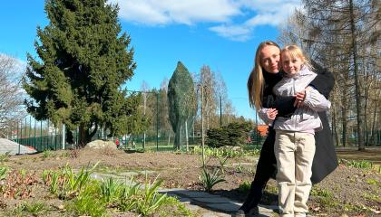 Vanhempi ja lapsi halaavat toisiaan keväisessä puistossa.