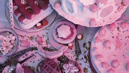 Installaatiossa on vaalenanpunaisia herkkuja kuten kakkuja ja leivoksia.