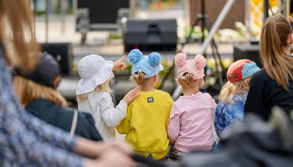 Kolme lasta katsomassa lavaohjelmaa Puistofiesta-tapahtumassa.